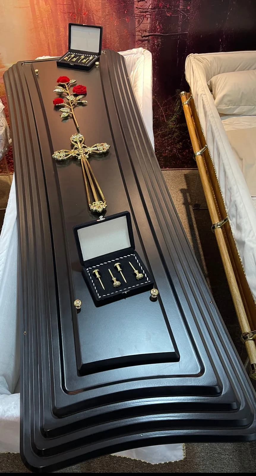 Urna funerária em tom grafite com aplicação floral de homenagem.