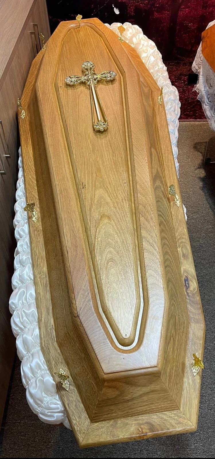 Urna funerária em madeira natural com crucifixo dourado.